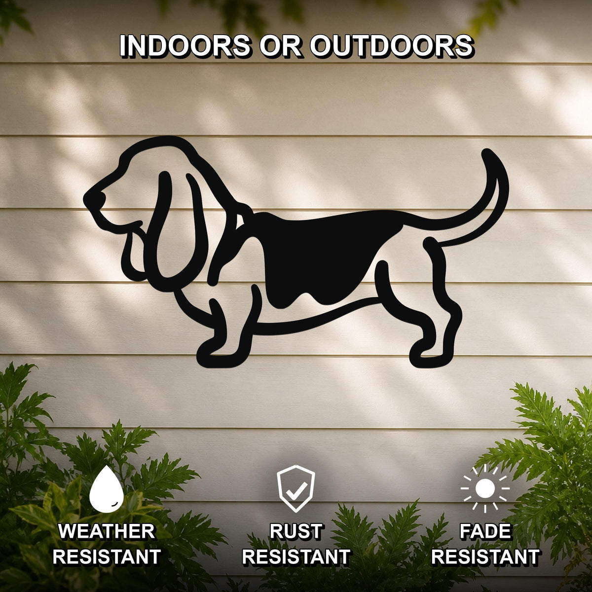 Black metal Basset Hound silhouette wall art mounted on a light-colored outdoor wall, with green plants at the base and text indicating it is weather, rust, and fade resistant.