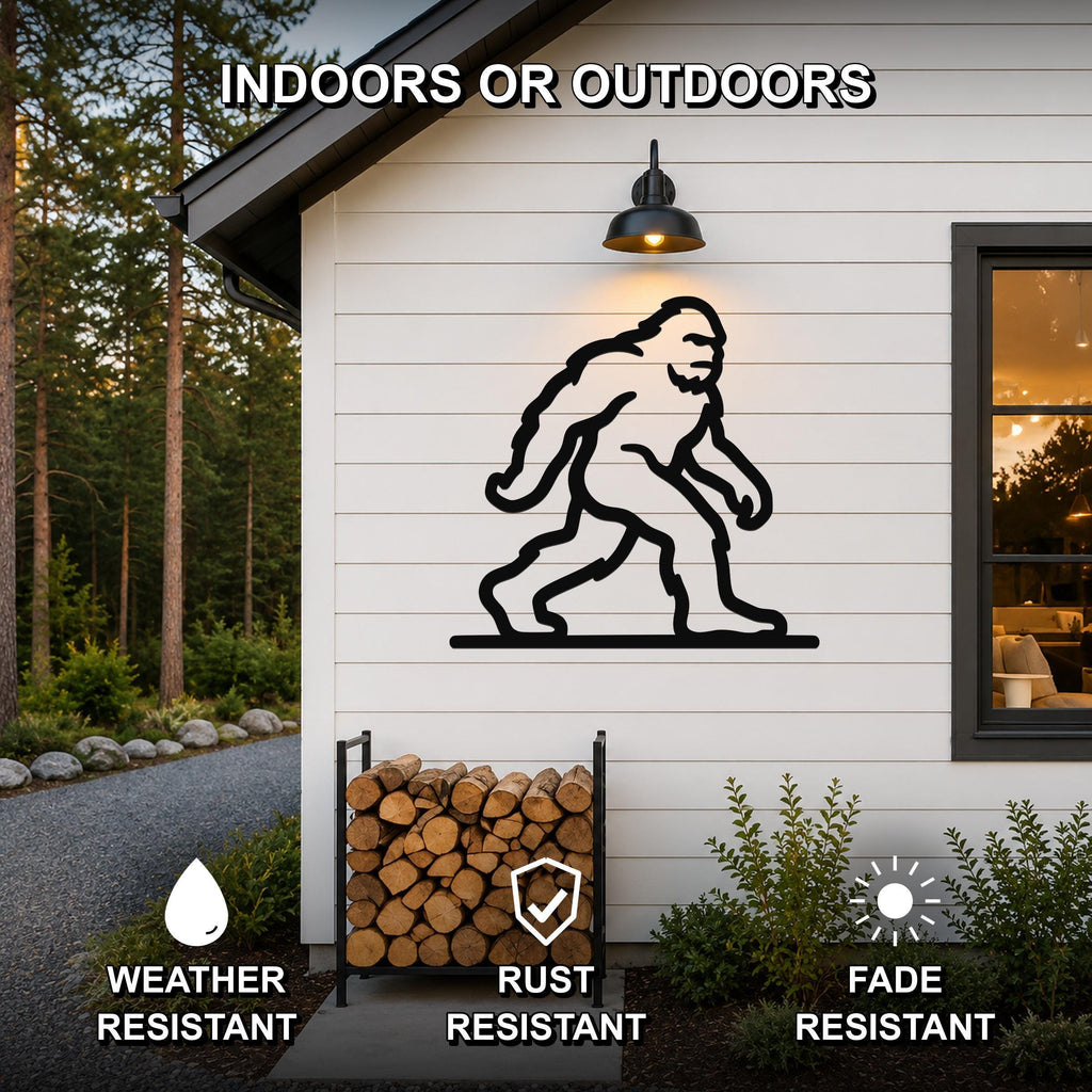 Black metal Bigfoot silhouette wall art mounted on a white exterior wall above a firewood rack, with text indicating it is weather, rust, and fade resistant for indoor or outdoor use.