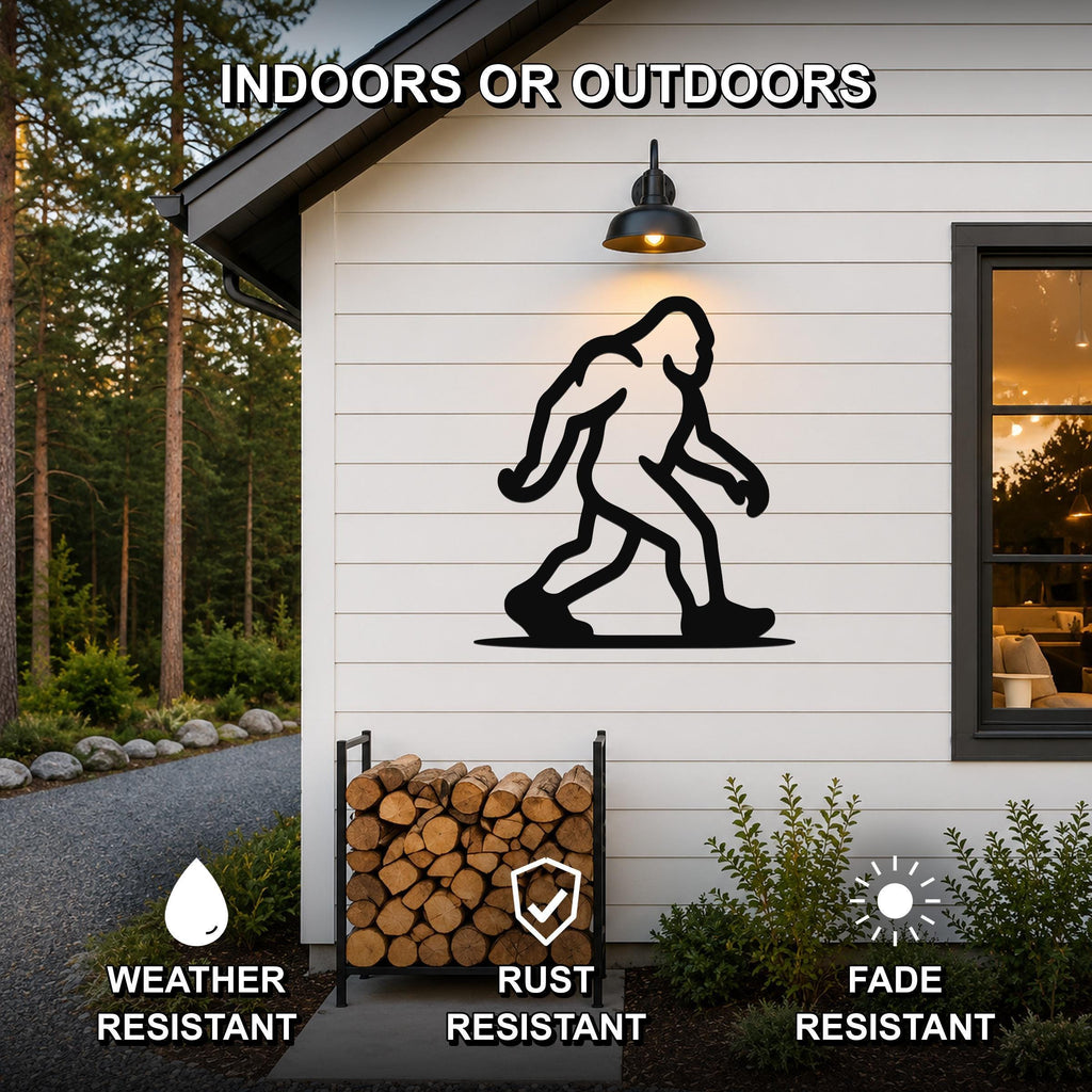 Black metal Bigfoot silhouette wall art mounted on a white siding exterior wall above a firewood rack, with a lit outdoor sconce above and a window to the right.