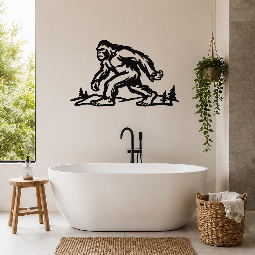 Black metal Bigfoot wall art silhouette with tree cutouts, mounted above a freestanding bathtub in a modern bathroom.