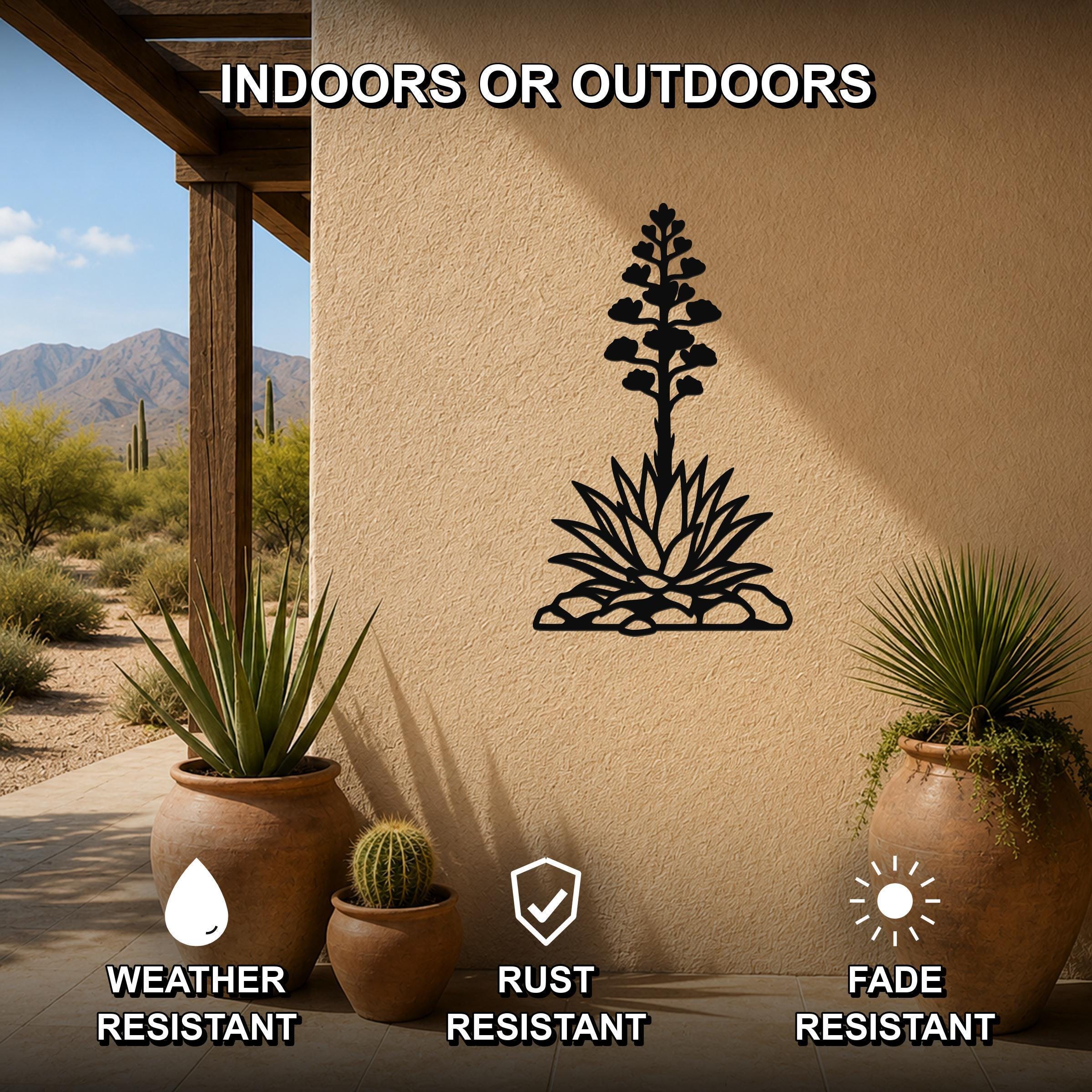 Black metal agave wall art with blooming flower and leaf cutouts, mounted on a stucco outdoor wall above potted plants on a patio.