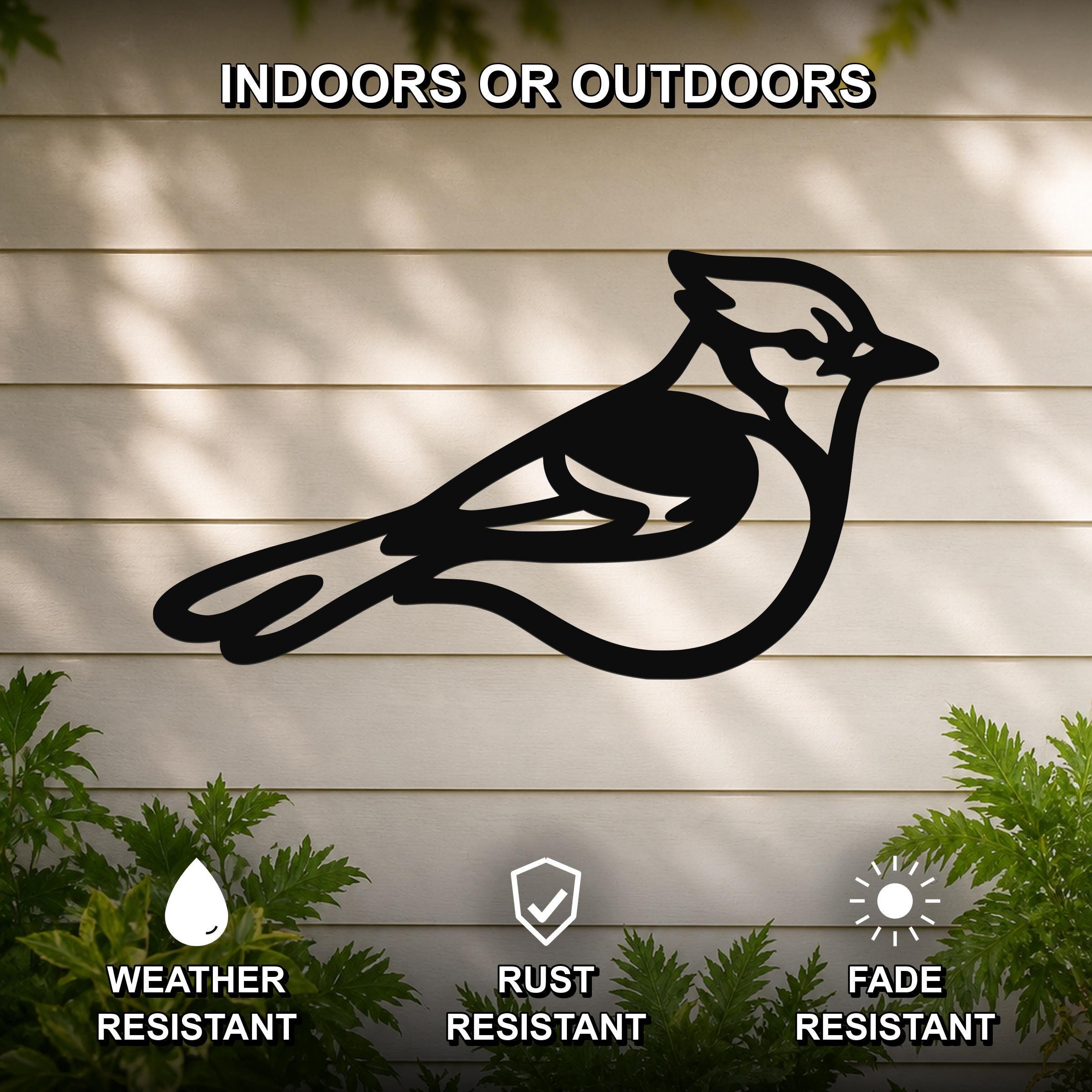 Black metal blue jay wall art silhouette mounted on a light-colored outdoor wall, with green plants at the base and text indicating it is weather, rust, and fade resistant.