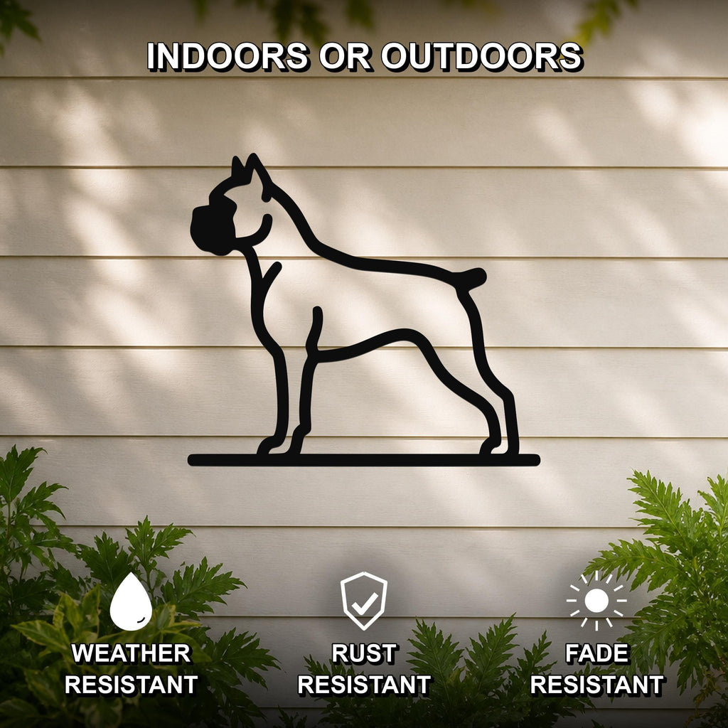 Black metal Boxer dog silhouette wall art mounted on a light-colored outdoor wall, with green plants visible below and text indicating it is weather, rust, and fade resistant.