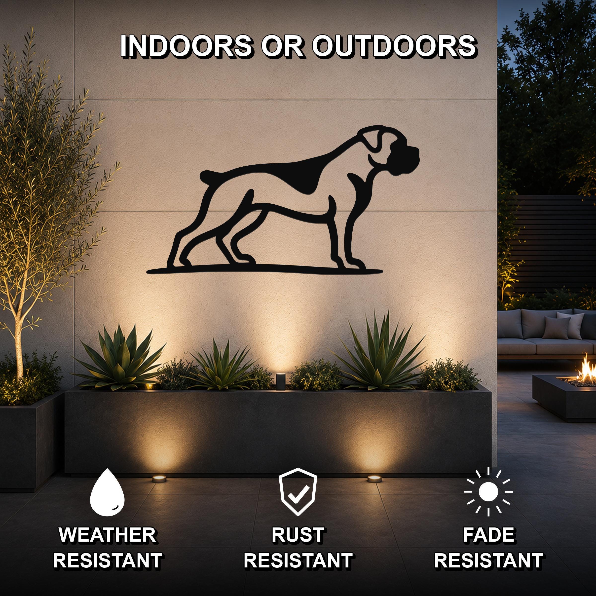 Black metal Boxer dog silhouette wall art mounted on an outdoor wall above a planter, with text indicating it is weather, rust, and fade resistant for indoor or outdoor use.