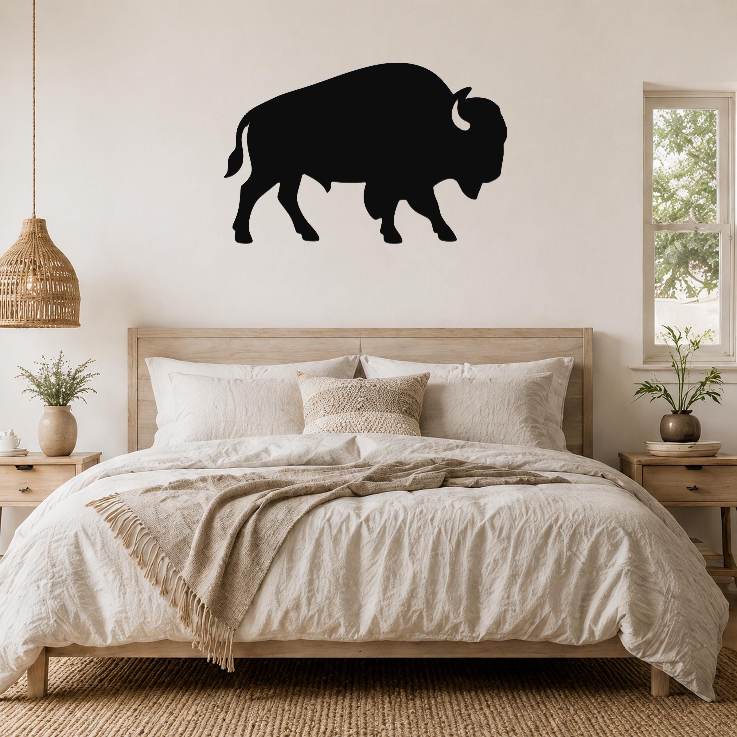 Black metal buffalo silhouette wall art mounted above a wooden bed in a neutral bedroom.