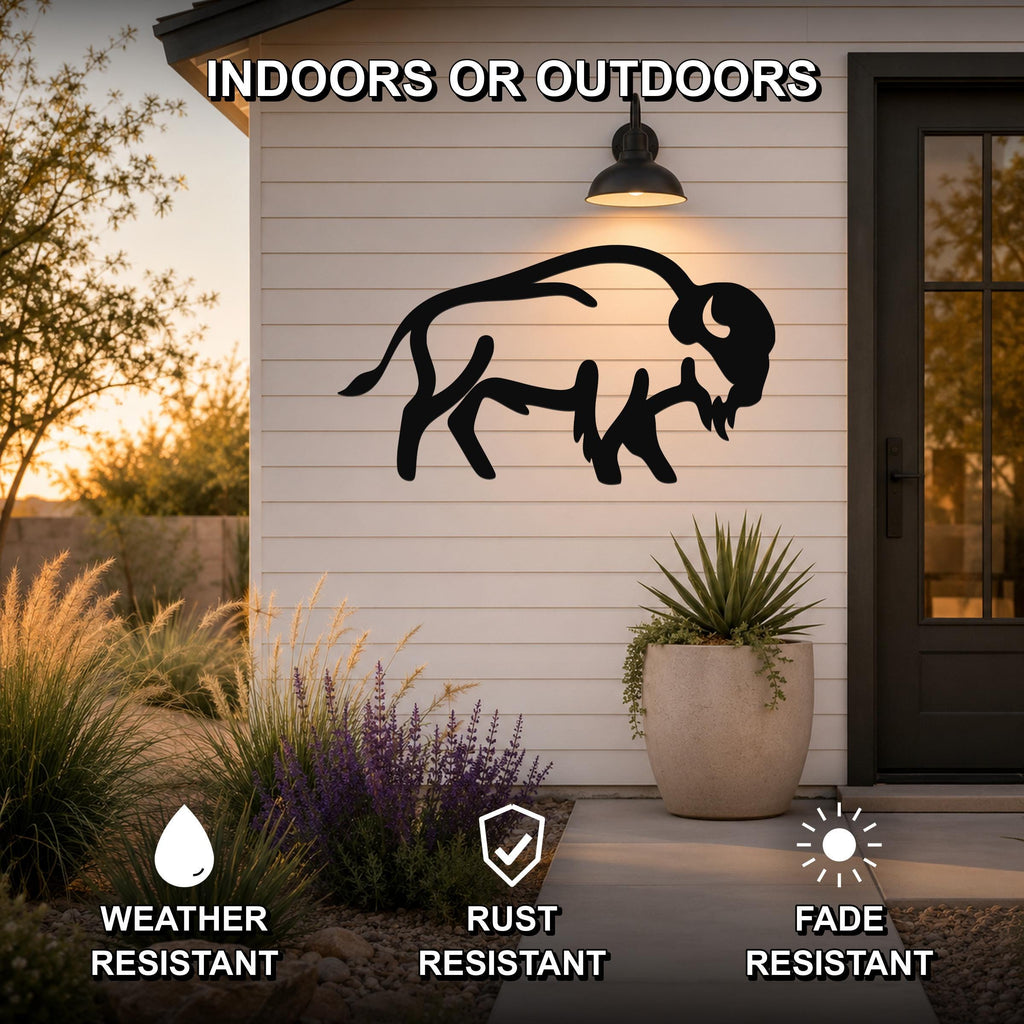 Black metal buffalo silhouette wall art mounted on a white siding exterior wall above a patio, with a potted plant and garden in the foreground.