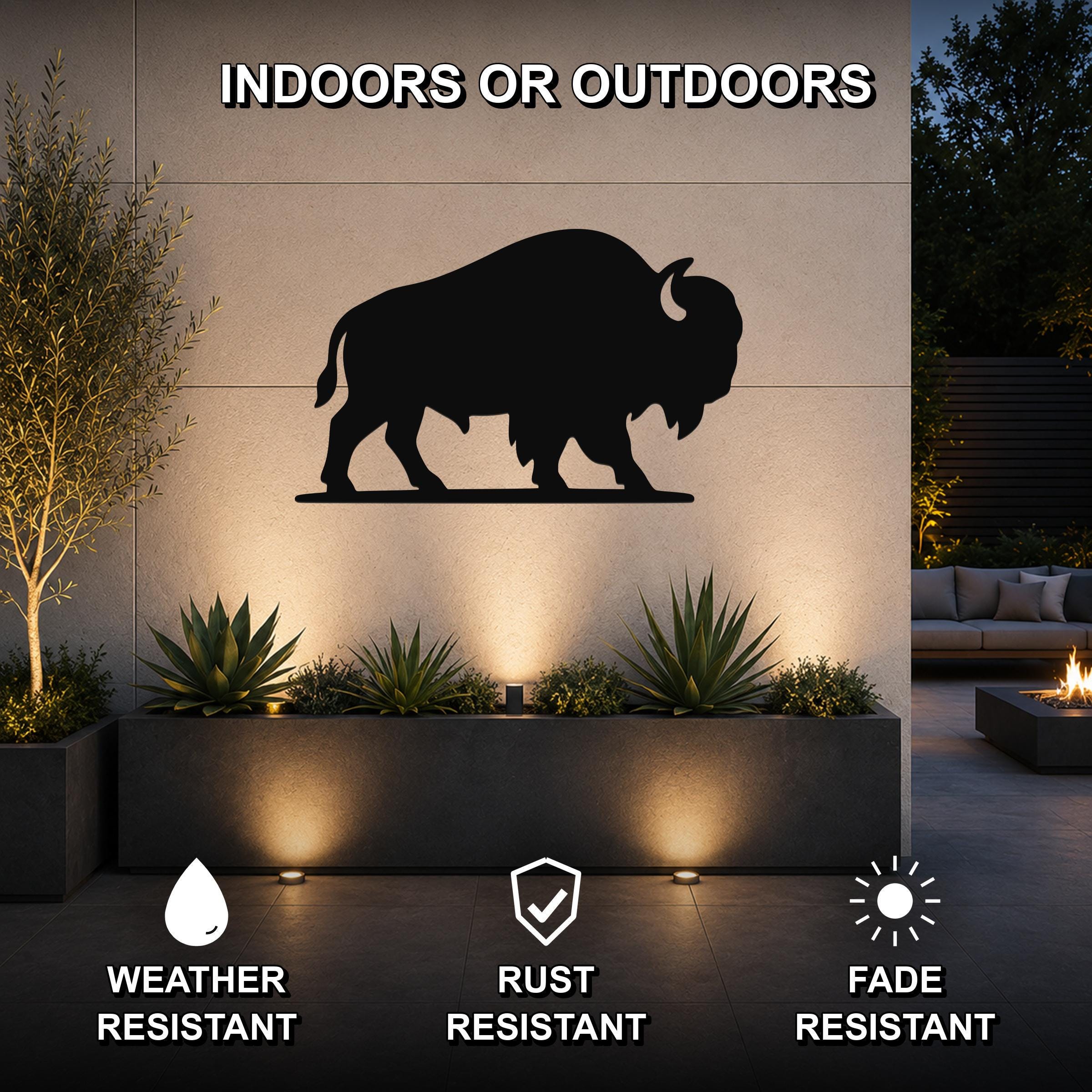 Black metal bison silhouette wall art mounted on an outdoor wall above a planter, with text indicating it is weather, rust, and fade resistant.