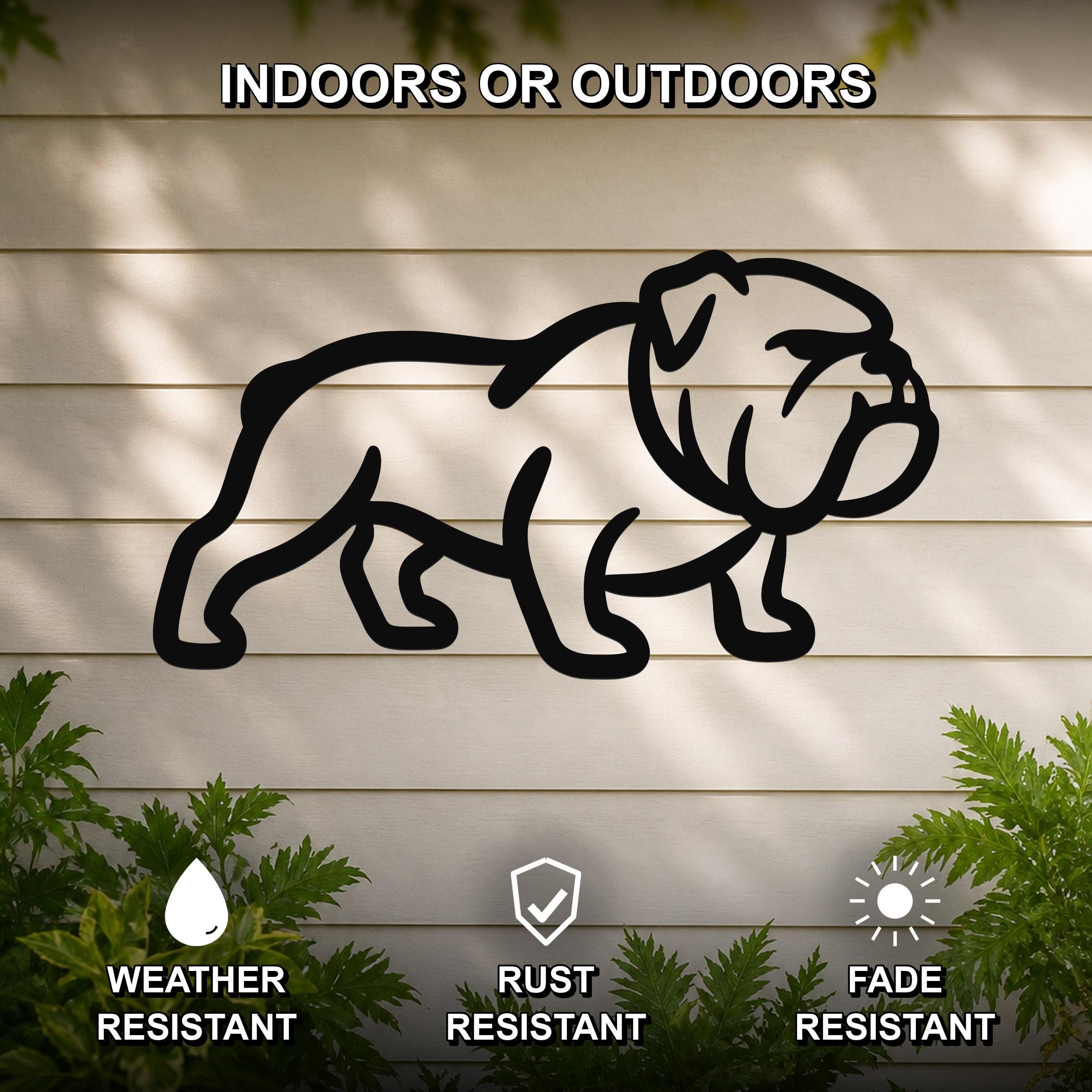 Black metal bulldog wall art silhouette mounted on a light-colored outdoor wall, with green plants at the base and text indicating it is weather, rust, and fade resistant.