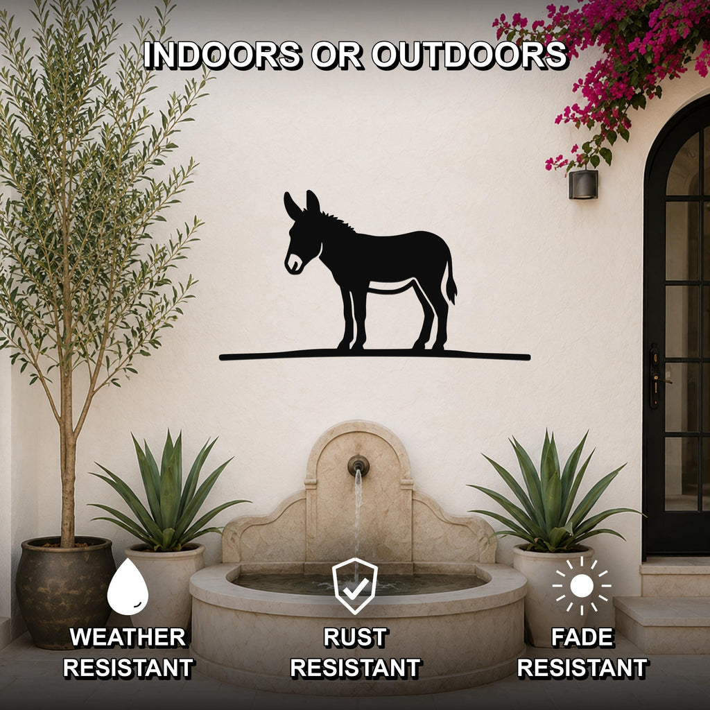 Black metal donkey wall art silhouette mounted on an outdoor wall above a stone fountain, flanked by potted plants and a flowering vine.