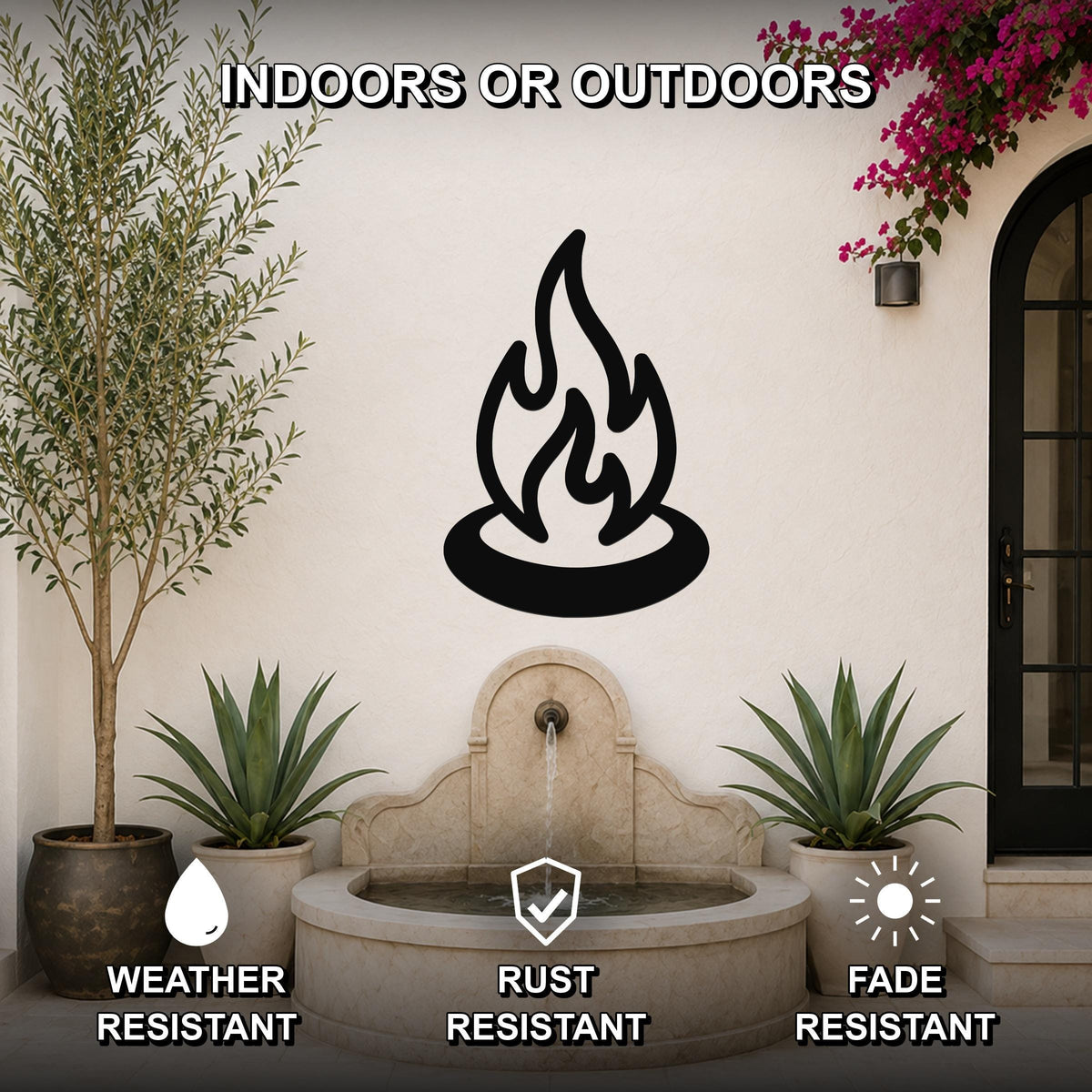 Black metal campfire wall art silhouette mounted on an outdoor patio wall above a stone fountain, flanked by potted plants and a flowering vine.