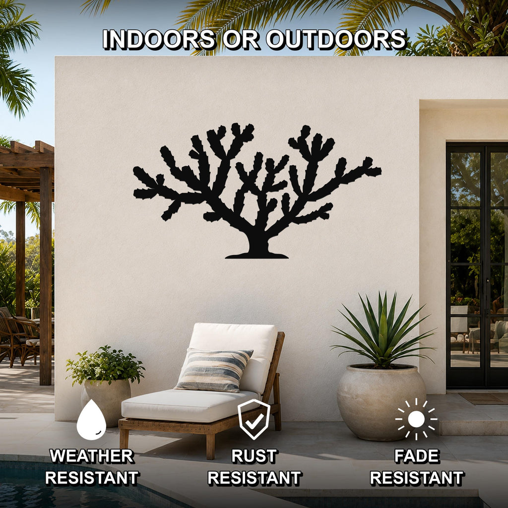 Black metal Cholla cactus wall art silhouette mounted on an outdoor patio wall, featuring branching cutouts and displayed above a lounge chair near a pool.