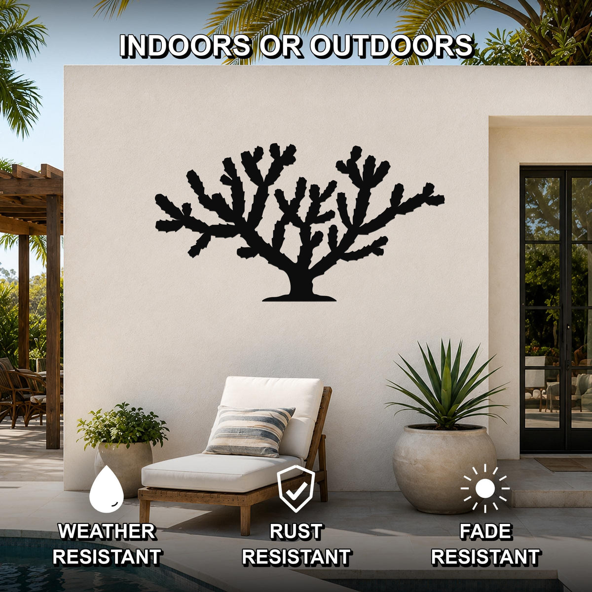 Black metal Cholla cactus wall art silhouette mounted on an outdoor patio wall, featuring branching cutouts and displayed above a lounge chair near a pool.