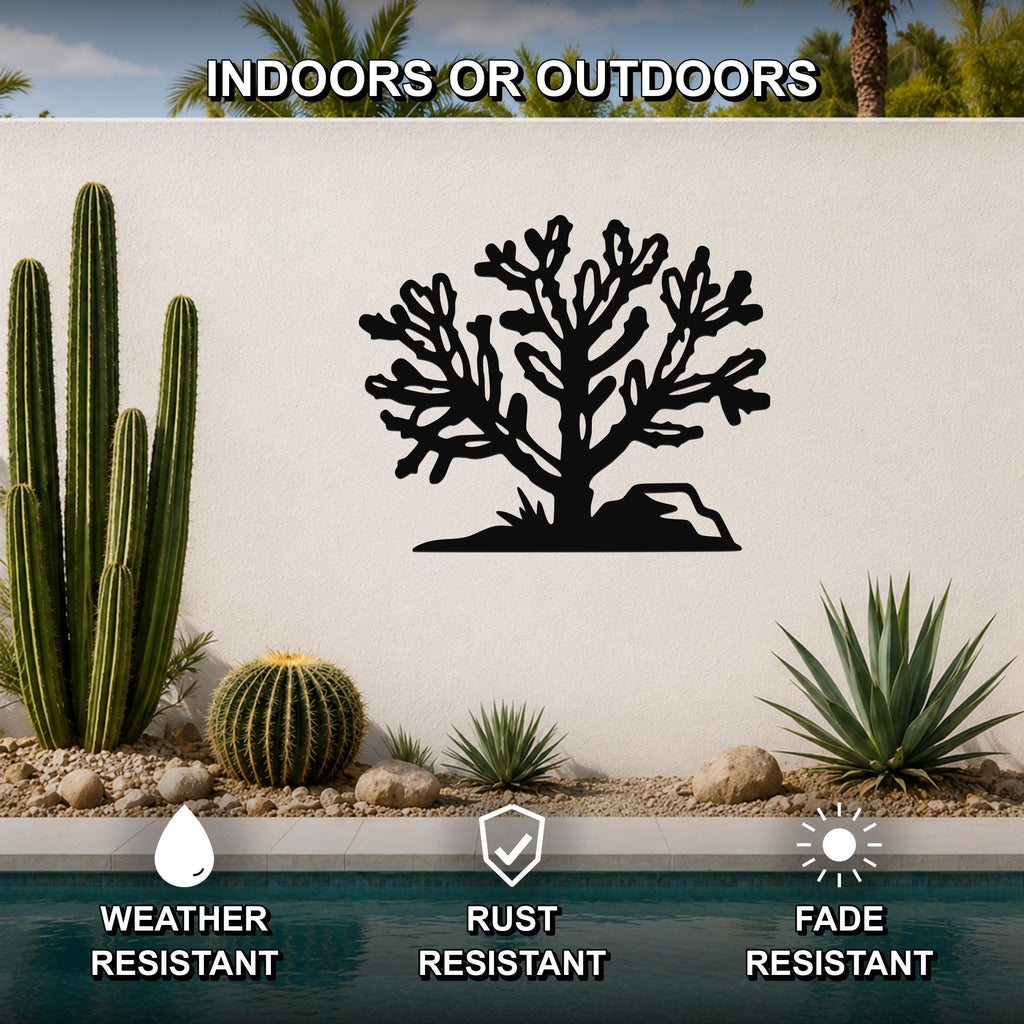Black metal Cholla cactus wall art with intricate branch cutouts, mounted on a white outdoor wall above a pool in a desert garden setting.