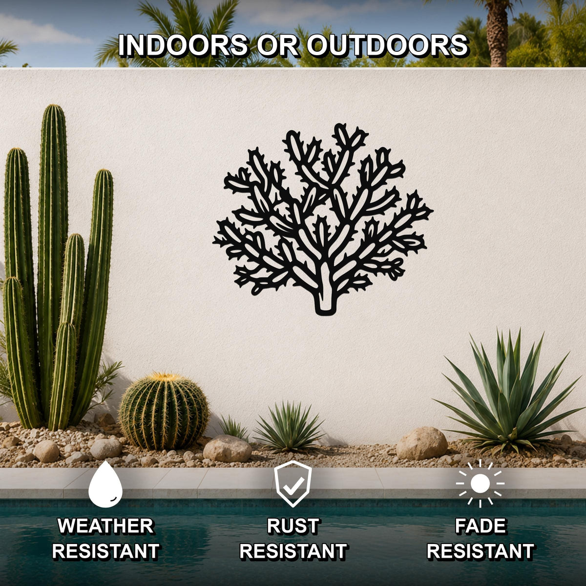Black metal Cholla cactus wall art with intricate branch cutouts, mounted on an outdoor wall above a pool in a desert garden setting.
