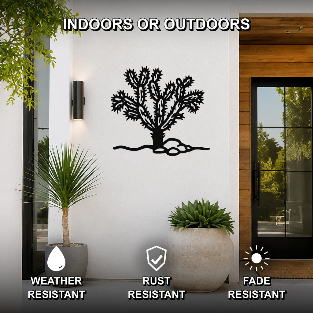 Black metal cholla cactus wall art with detailed branch cutouts, mounted on a white exterior wall beside a glass door and potted plants.