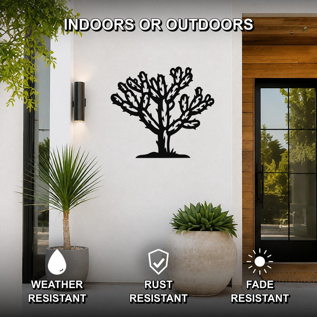 Black metal cholla cactus wall art with detailed branch cutouts, mounted on a white exterior wall beside a glass door and potted plants.