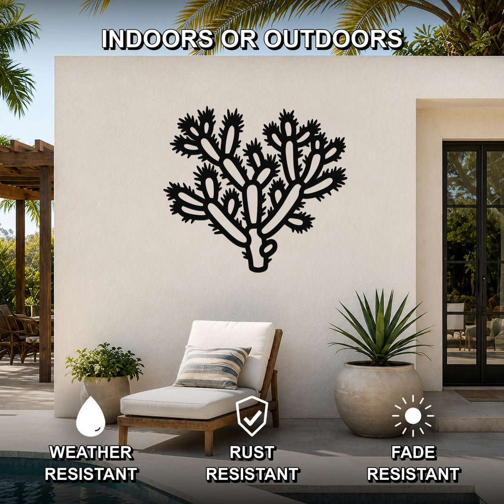 Black metal cholla cactus wall art with detailed branch cutouts, mounted on an outdoor patio wall above a lounge chair.