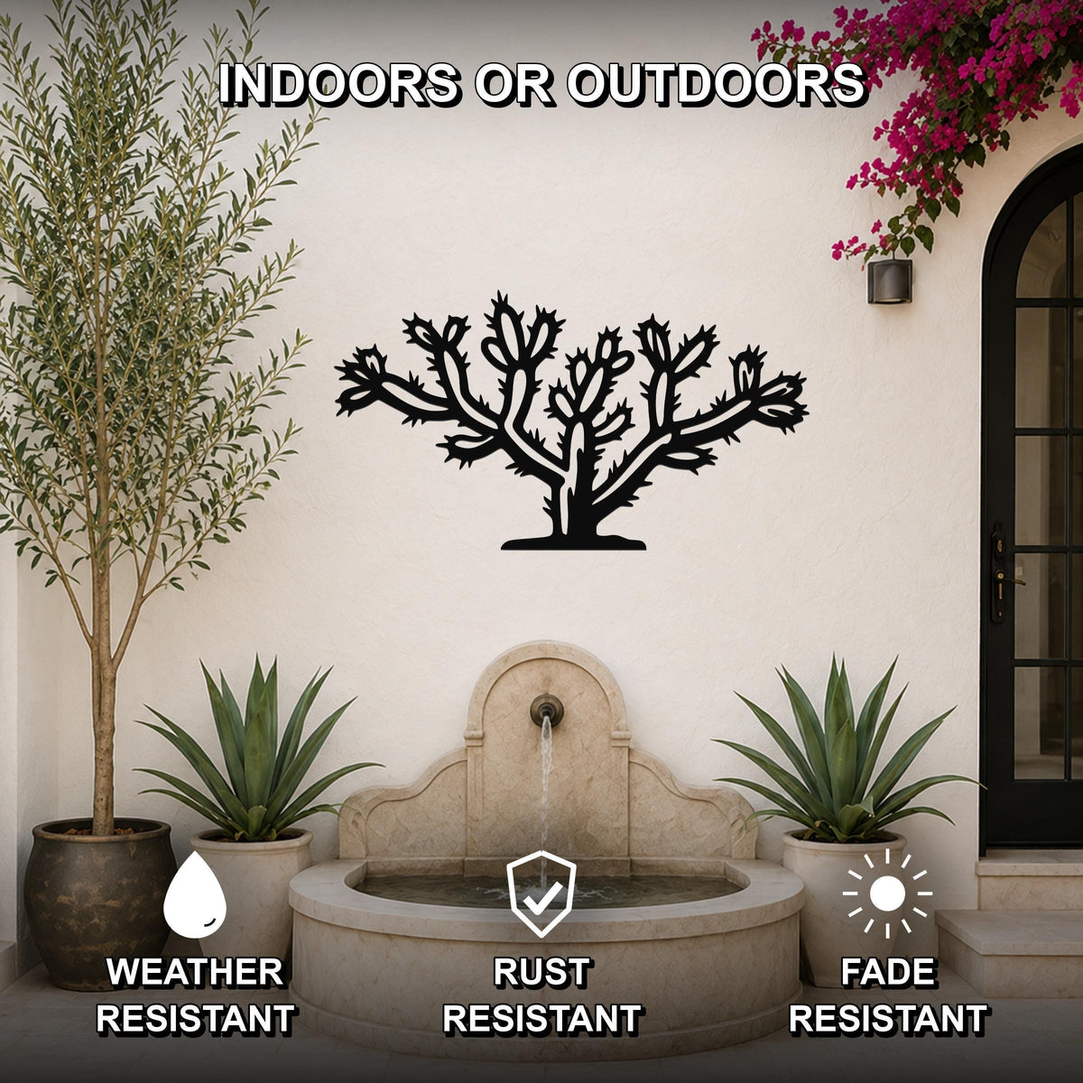 Black metal cholla cactus wall art with spiny branch cutouts, mounted on an outdoor wall above a stone fountain in a patio setting.