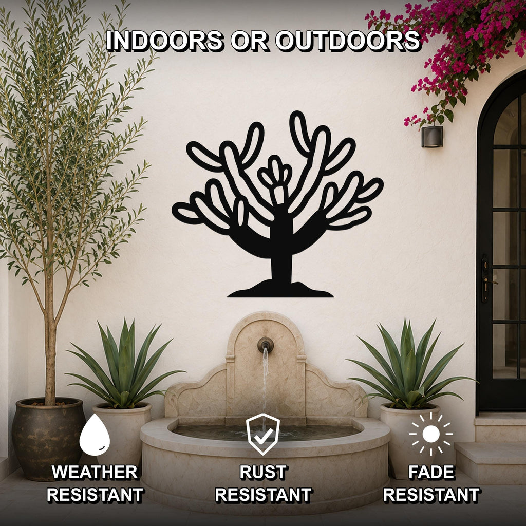 Black metal Cholla cactus wall art with branching cutouts, mounted on an outdoor patio wall above a stone fountain.