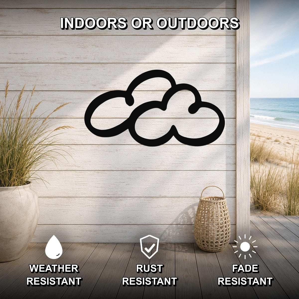 Black metal cloud wall art with a cutout silhouette, mounted on a light wood plank wall in a coastal indoor-outdoor space with a view of the beach.