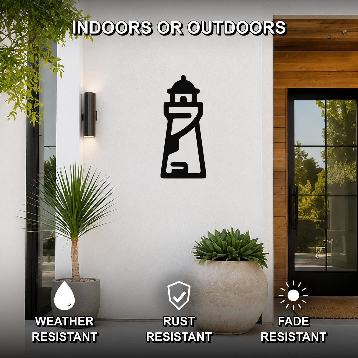 Black metal lighthouse wall art with internal cutout details, mounted on a white exterior wall beside a glass door and potted plants, suitable for indoor or outdoor use.