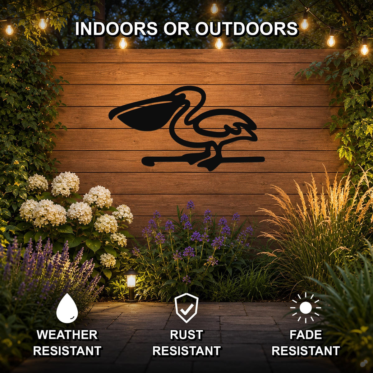 Black metal pelican wall art silhouette mounted on a wooden outdoor wall, surrounded by garden plants and string lights, with text indicating it is weather, rust, and fade resistant.