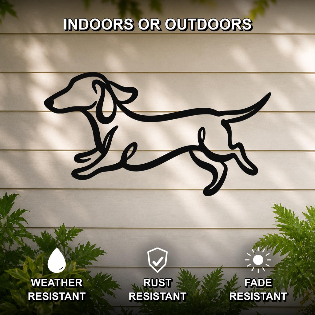 Black metal dachshund wall art with bold line cutout design, mounted on a light-colored outdoor wall with greenery, weather resistant, rust resistant, and fade resistant.