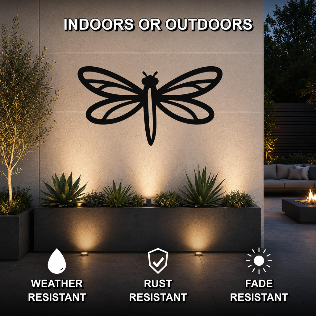 Black metal dragonfly wall art with detailed wing cutouts, mounted on an outdoor wall above a planter in a modern patio setting.