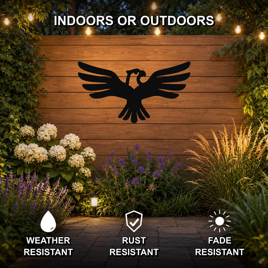 Black metal eagle wall art with outstretched wings silhouette, mounted on a wooden outdoor wall above a garden with flowers and string lights.