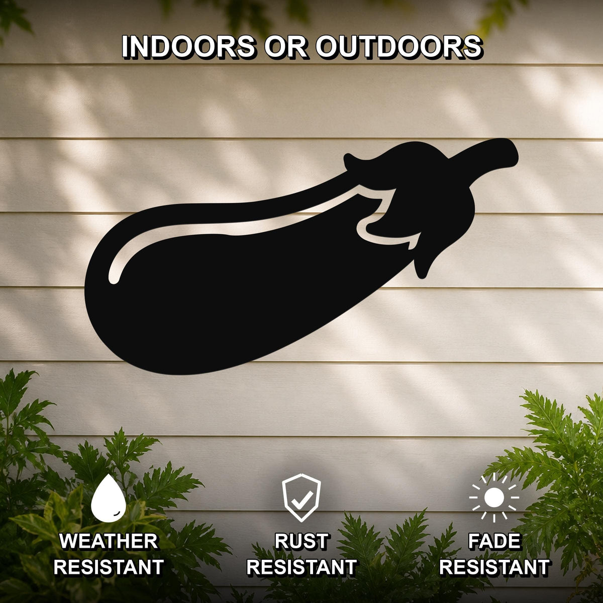 Black metal eggplant wall sculpture with a smooth silhouette, mounted on a light-colored outdoor wall with greenery below, weather resistant, rust resistant, and fade resistant.