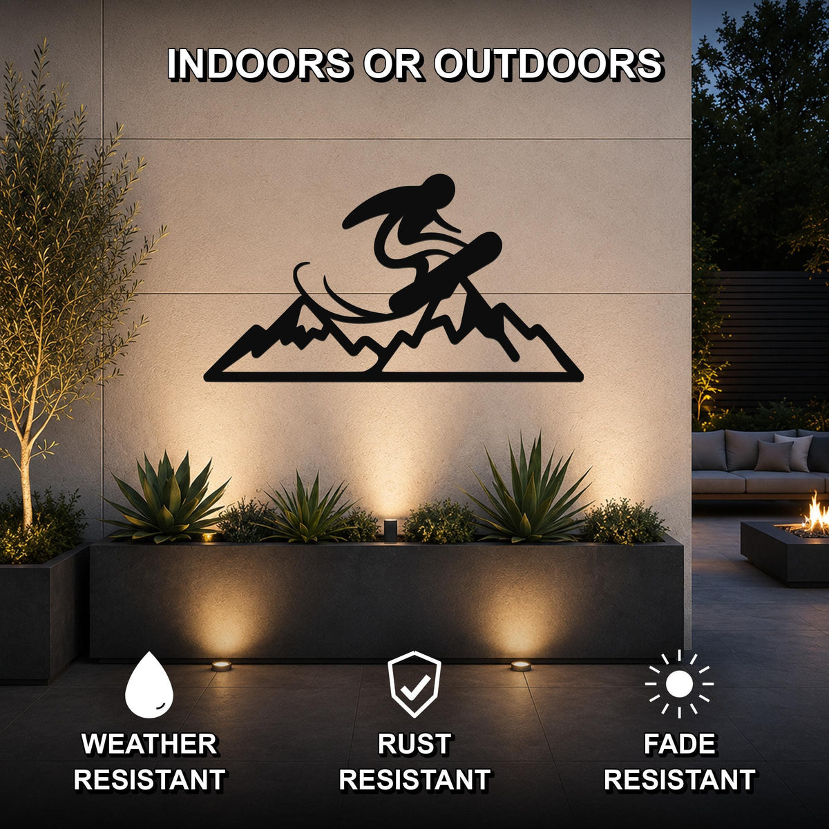 Black metal wall art featuring a snowboarder silhouette above a mountain range, mounted on an outdoor wall above a planter in a modern patio setting.