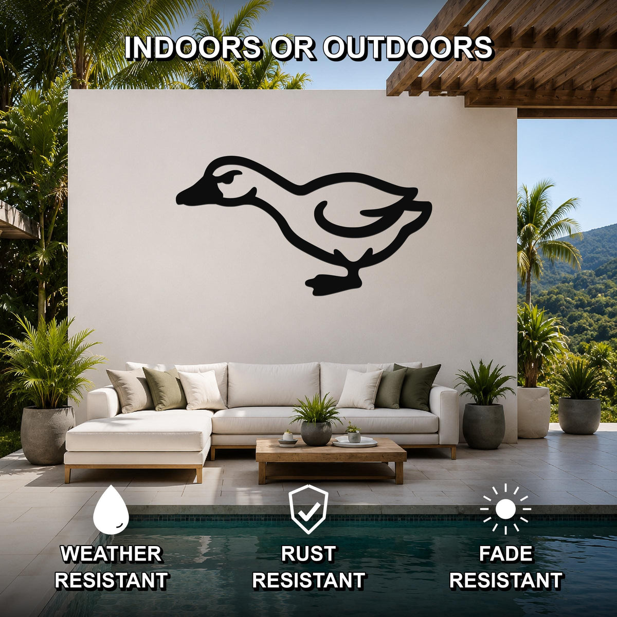Black metal goose silhouette wall art mounted on a white outdoor wall above a white sofa in a patio living area.