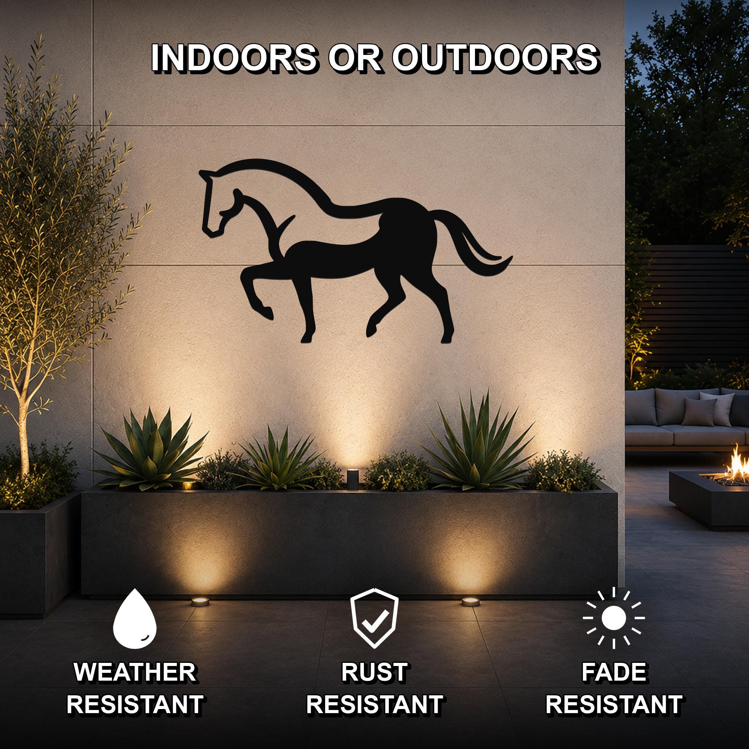 Black metal horse silhouette wall art mounted on an outdoor wall above a planter, with lighting highlighting the cutout design.
