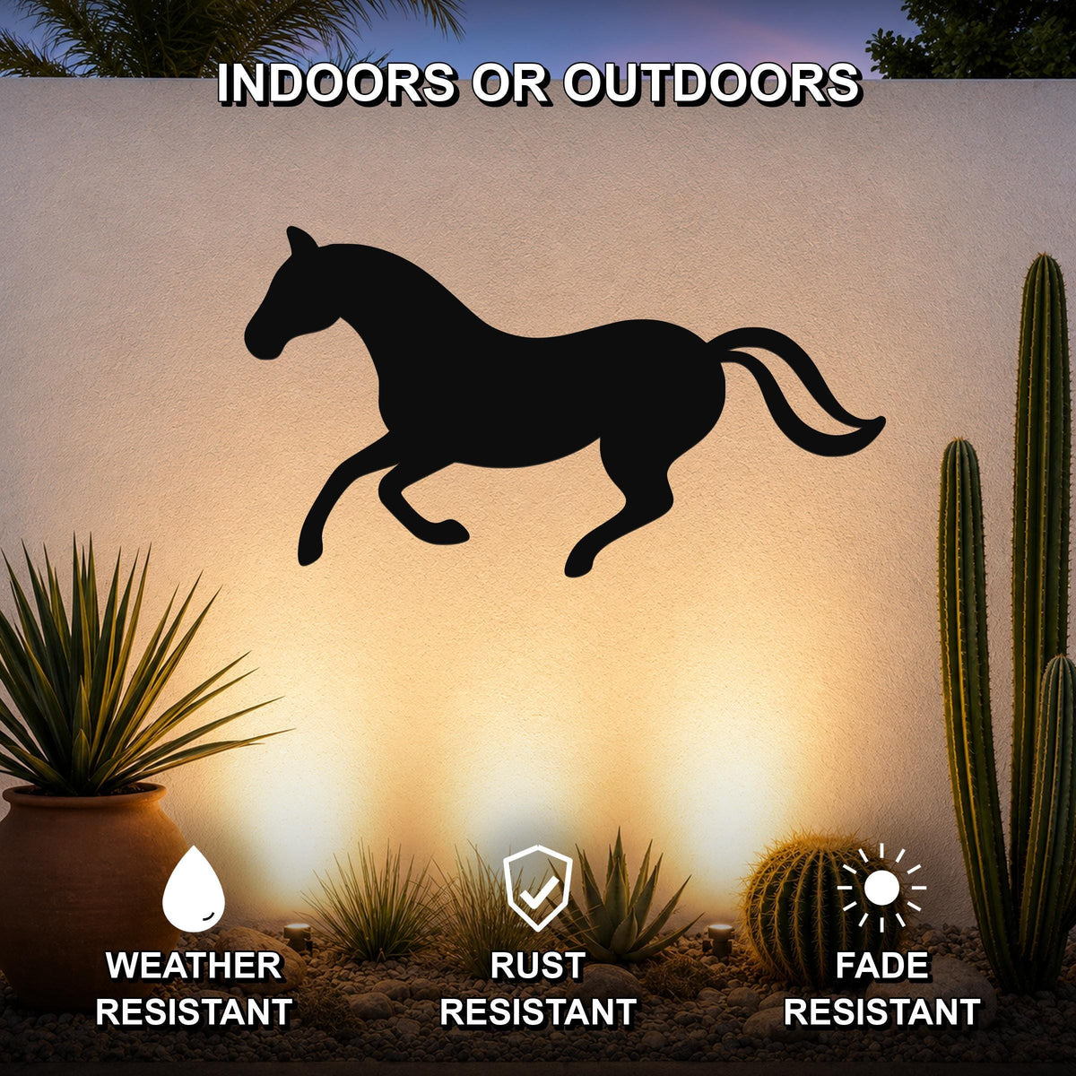 Black metal horse wall art silhouette in a running pose, mounted on an outdoor wall above a desert garden with cacti and rocks.