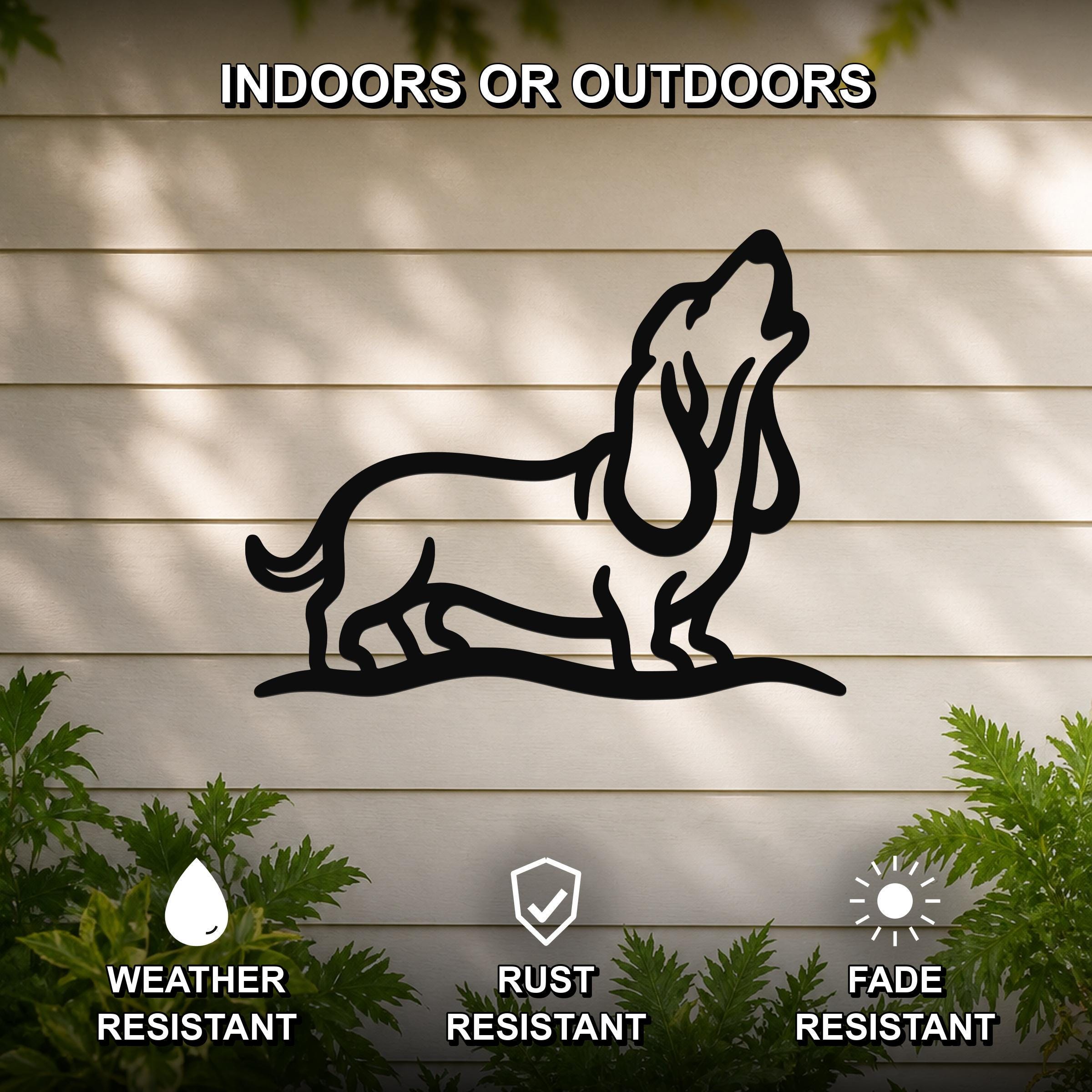 Black metal wall art featuring a bold silhouette of a howling basset hound, mounted on a light-colored outdoor wall with greenery below.