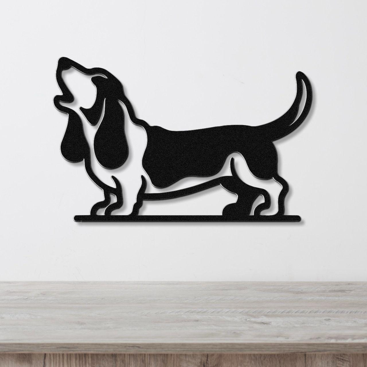 Black metal wall art silhouette of a basset hound howling, mounted on a white wall above a light wood surface.