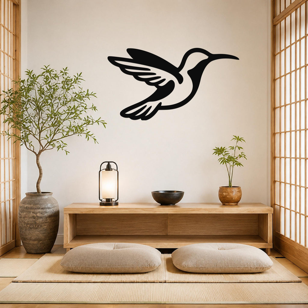 Black metal hummingbird wall art with wing and tail cutouts, mounted on a light wall above a wooden console in a minimalist room.
