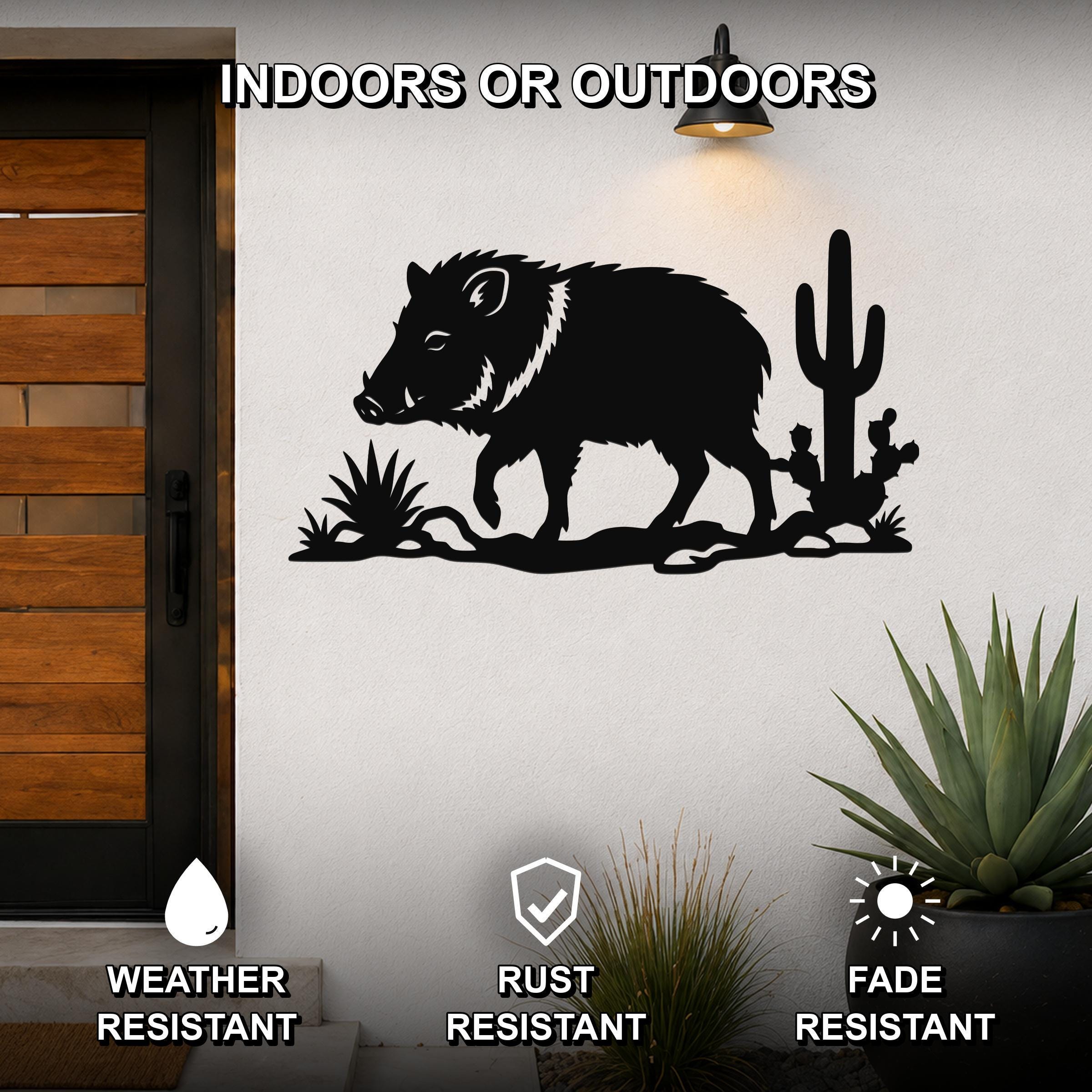 Black metal wall art featuring a javelina silhouette with cacti, mounted on an outdoor wall beside a wooden door, weather, rust, and fade resistant.