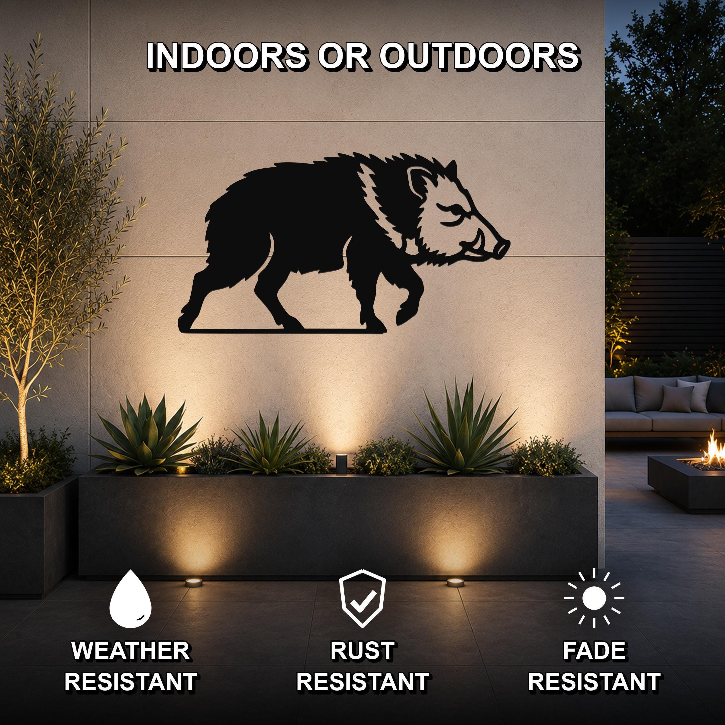 Black metal javelina wall art silhouette mounted on an outdoor wall above a planter, with text indicating it is weather, rust, and fade resistant for indoor or outdoor use.