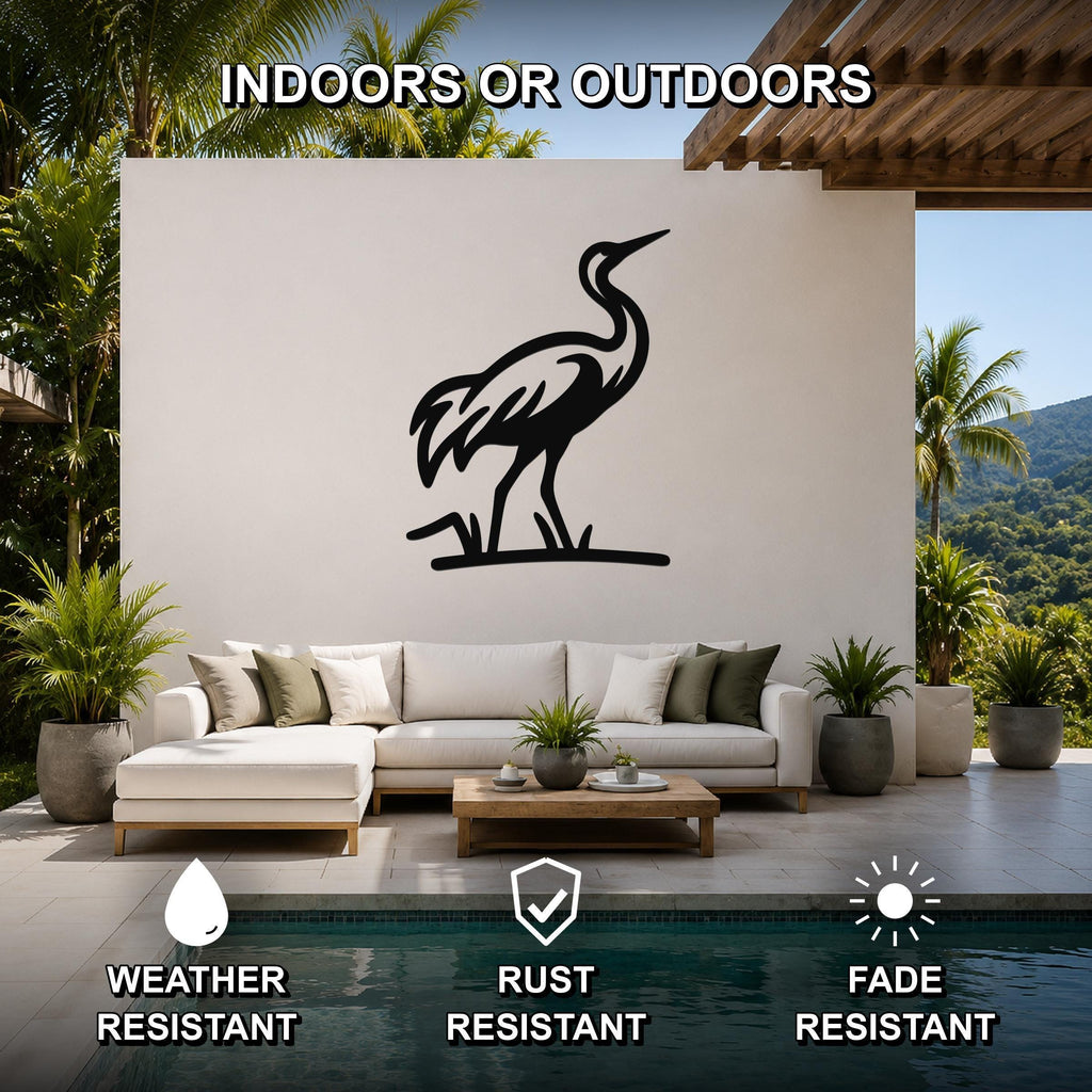 Black metal crane wall art silhouette mounted on a white outdoor wall above a white sectional sofa in a patio living area.