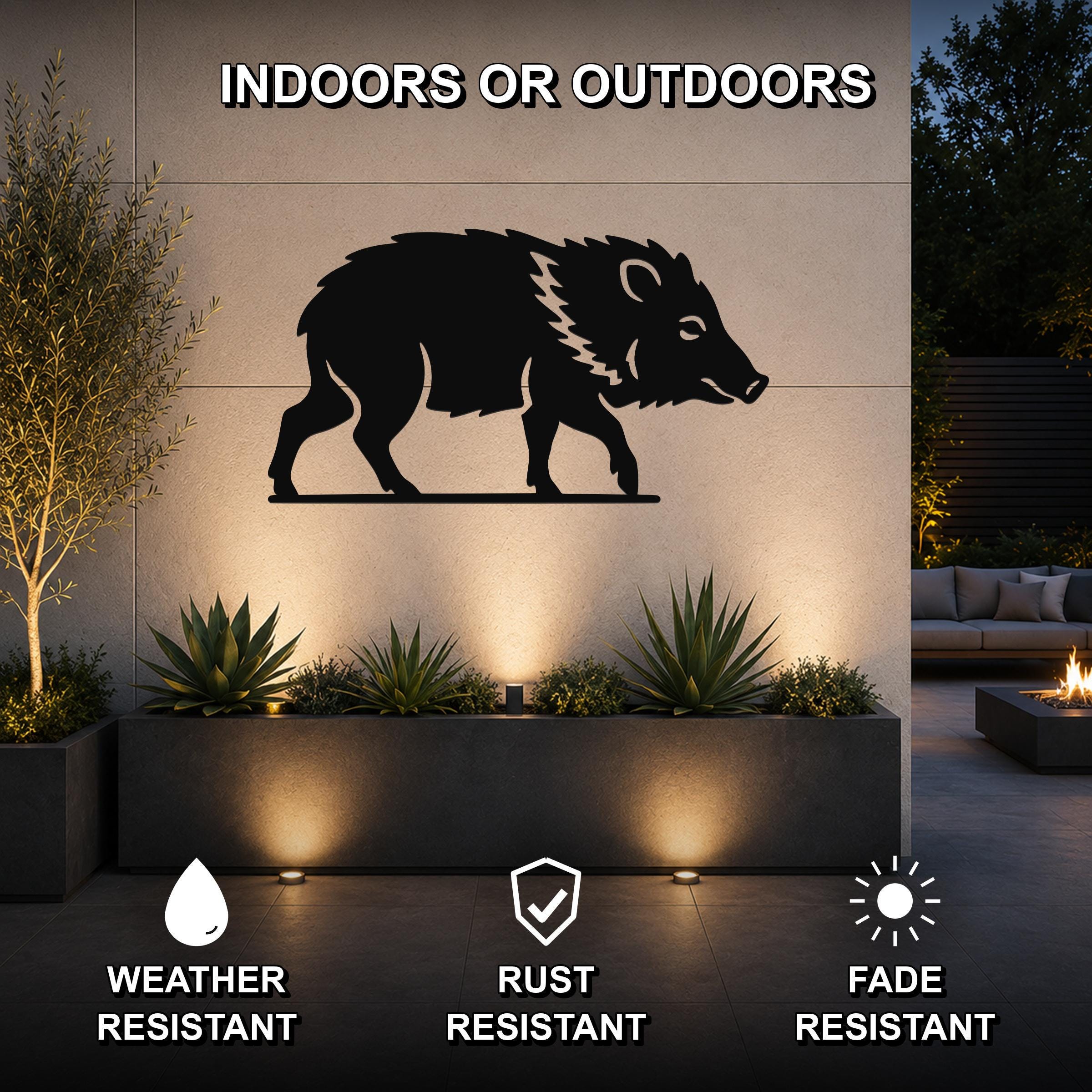 Black metal javelina wall art silhouette mounted on an outdoor wall above a planter, with text indicating it is weather, rust, and fade resistant.