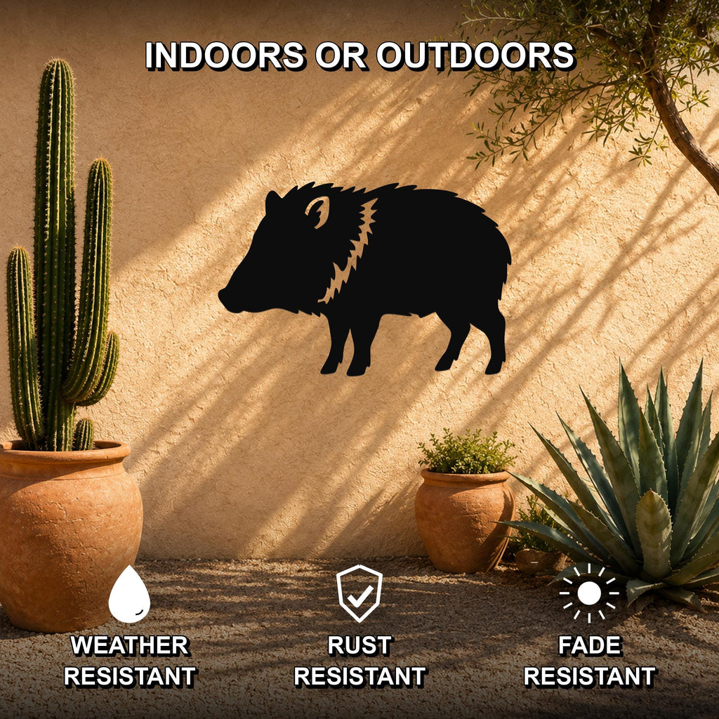 Black metal javelina wall art silhouette with textured mane detail, mounted on an outdoor stucco wall beside potted cacti and succulents.