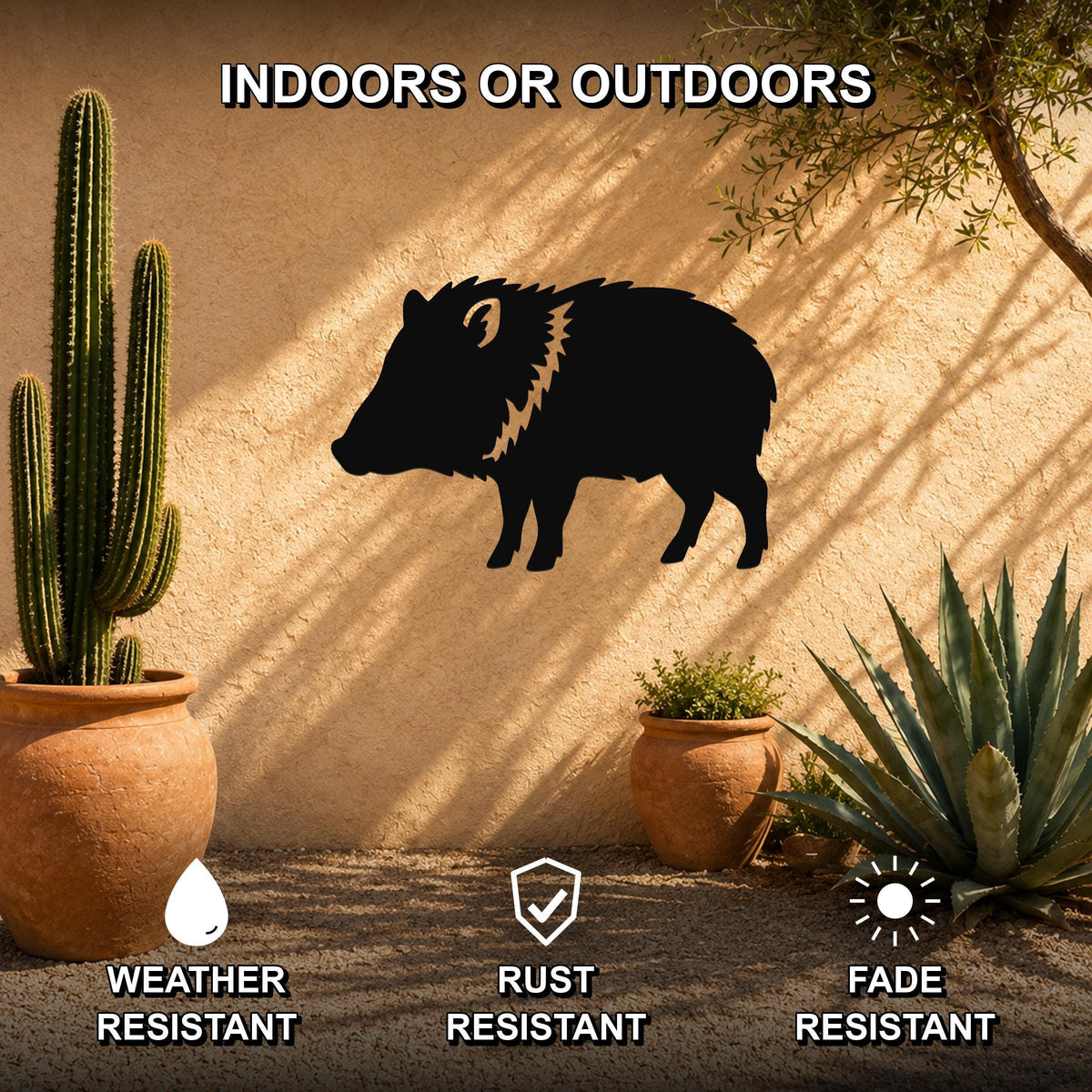 Black metal javelina wall art silhouette with textured mane detail, mounted on an outdoor stucco wall beside potted cacti and succulents.