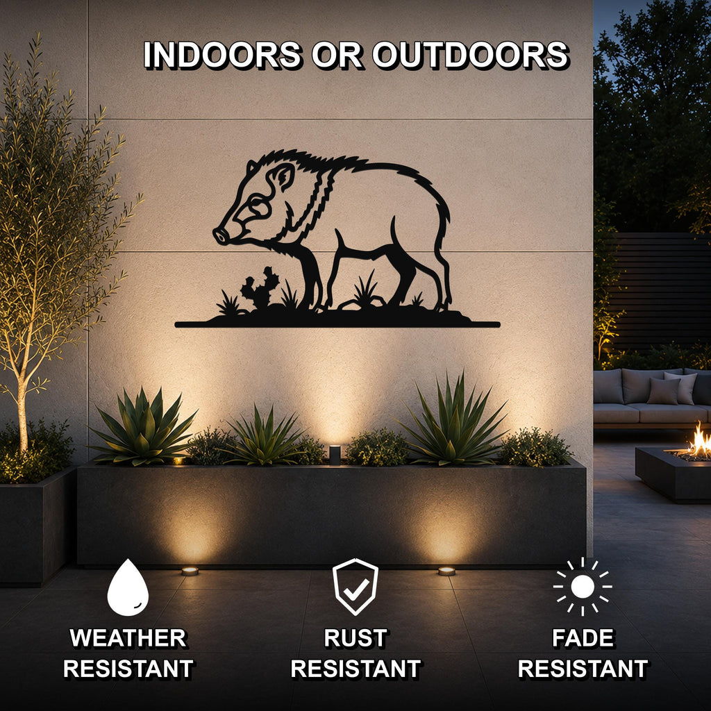 Black metal javelina wall art silhouette with cactus and grass cutouts, mounted on an outdoor wall above a planter in a patio setting.