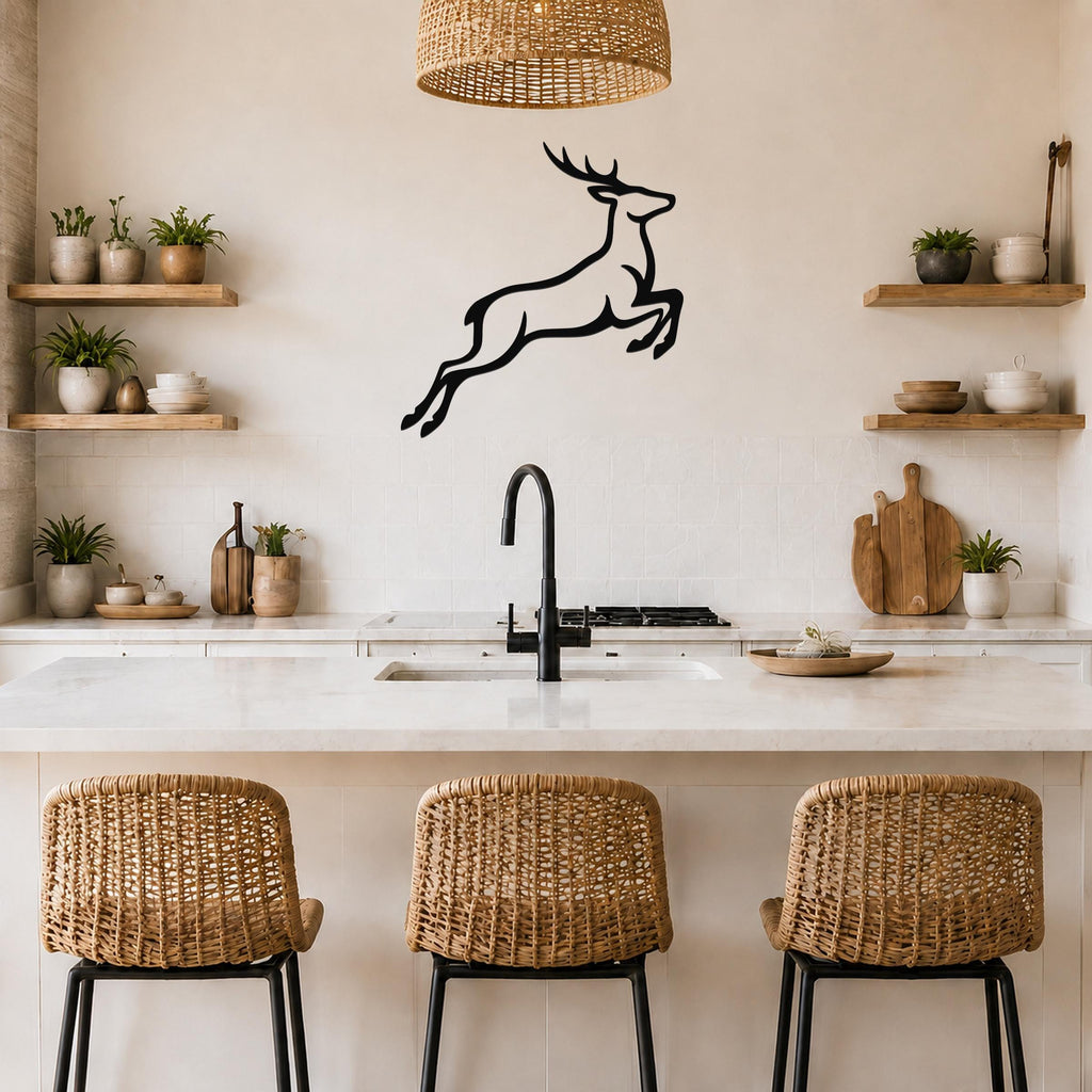 Black metal jumping deer wall art silhouette mounted above a kitchen counter, displayed in a modern kitchen with wooden shelves and wicker bar stools.