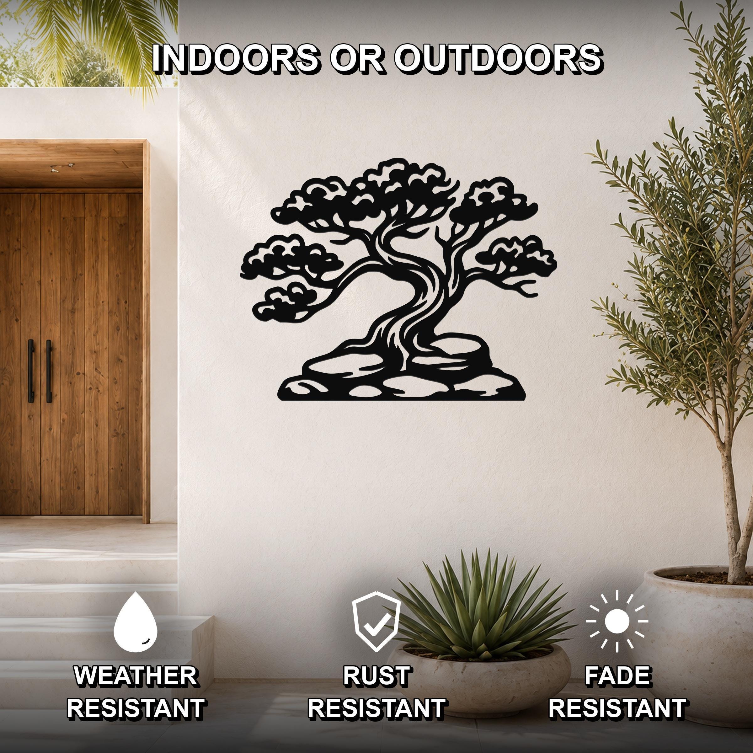 Black metal juniper tree wall art with intricate branch and cloud cutouts, mounted on a white wall in a modern entryway with potted plants and a wooden door.