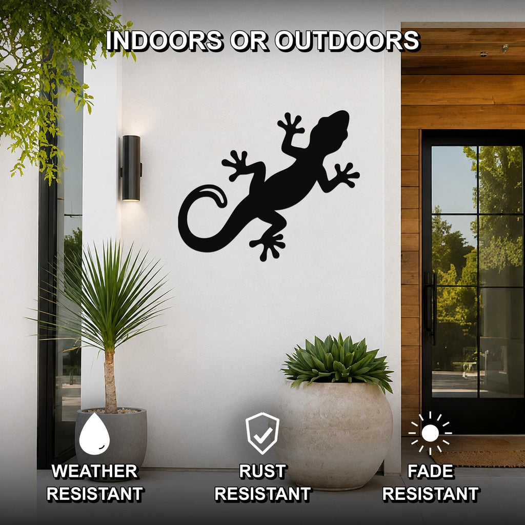 Black metal lizard wall art silhouette mounted on a white exterior wall beside a glass door, with potted plants nearby and text indicating it is weather, rust, and fade resistant for indoor or outdoor use.