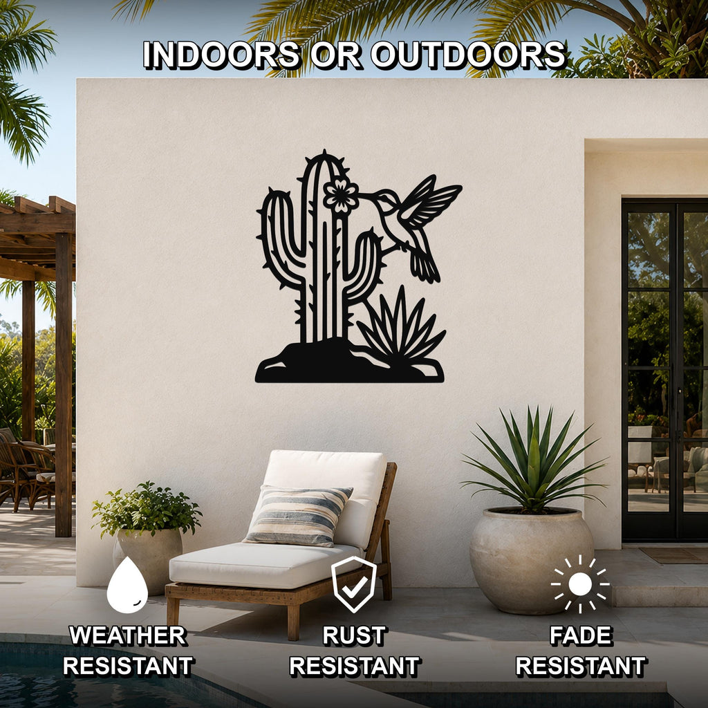 Black metal wall art featuring a cactus and hummingbird silhouette, mounted on an outdoor patio wall above a lounge chair.