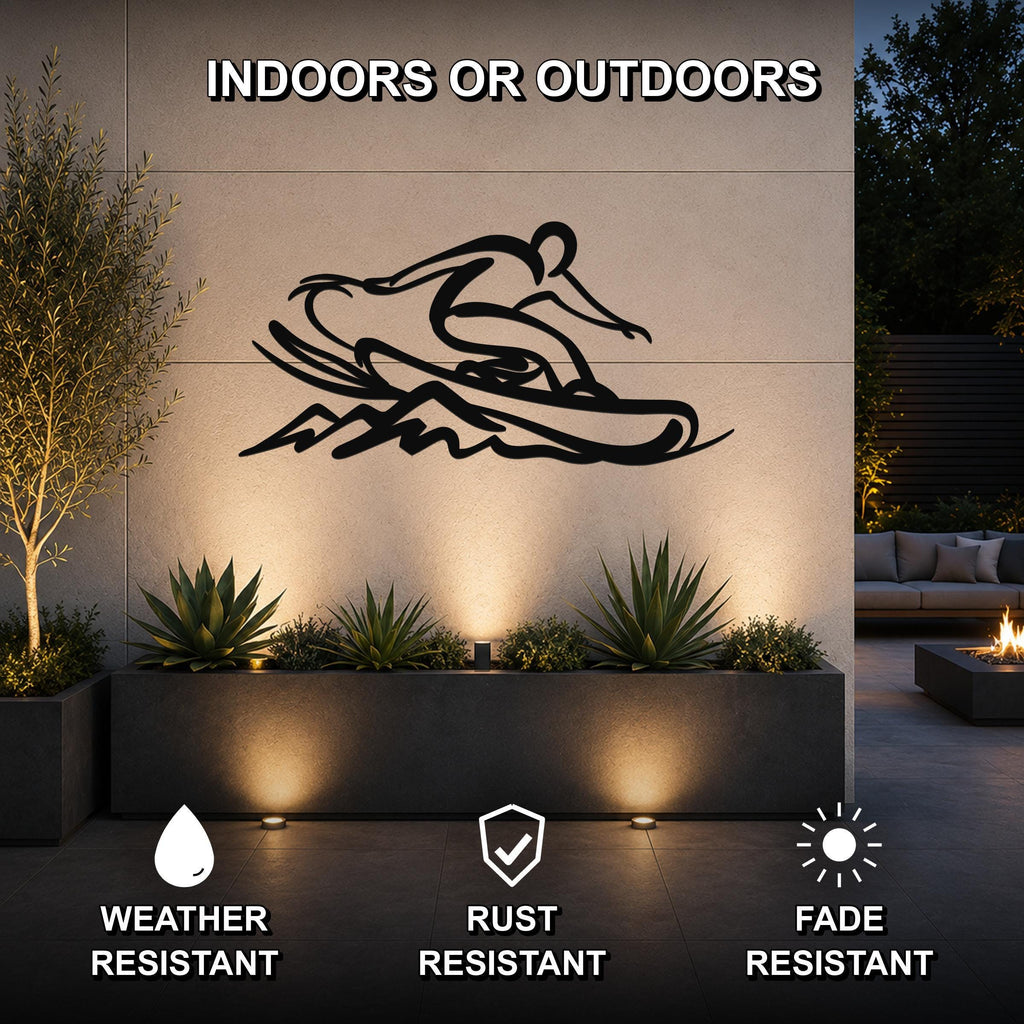 Black metal wall art of a snowboarder silhouette with motion lines, mounted on an outdoor wall above a planter in a patio setting.