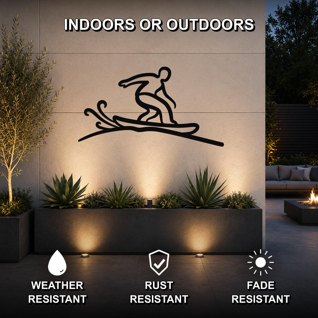 Black metal wall art silhouette of a snowboarder in motion, mounted on an outdoor wall above a planter with succulents, illuminated by ground lights.